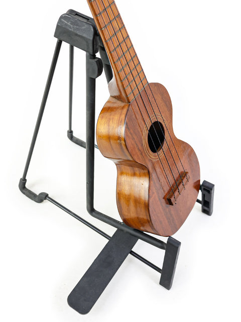 classic Kumalae ukulele from the 1920s is displayed on a stand, reflecting its rich history and Hawaiian musical roots.
