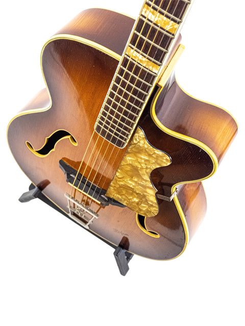 1950s Hofner 455 Archtop guitar featuring a rich brown body and elegant gold hardware, a true vintage gem from Germany.