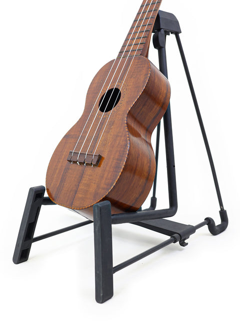 A 1927 Paul F. Summers 'Moana' Style 5 Koa Ukulele displayed on a stand, showcasing its vintage charm.