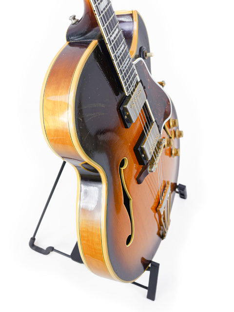 A 1966 Vintage Gibson Byrdland guitar elegantly displayed on a stand, contrasting beautifully with a white backdrop.