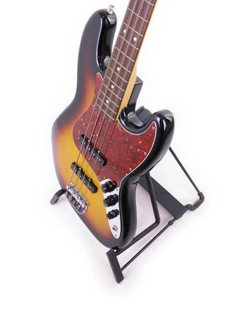 A 2013 Fender Jazz Bass guitar displayed on a stand, set against a bright white backdrop, highlighting its elegant features.