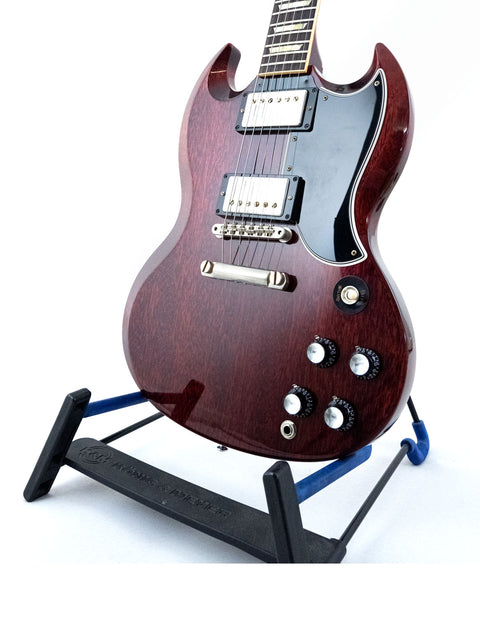 A Gibson Custom ’61 Les Paul SG Standard guitar resting on a stand with a black base, emphasizing its classic and iconic look.