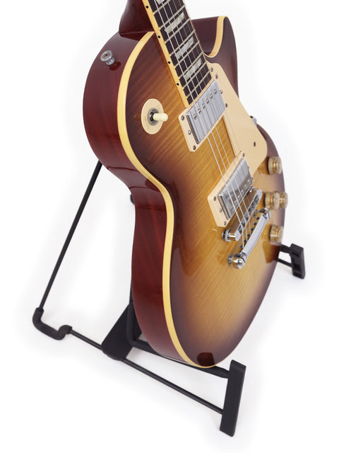 A Gibson Les Paul Traditional guitar from 2009 rests on a stand, highlighted by a simple white backdrop.