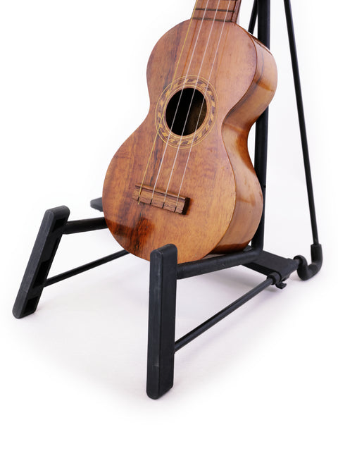 A Kumalae Style 2 ukulele from 1913 sits on a stand, representing traditional Hawaiian music and craftsmanship.