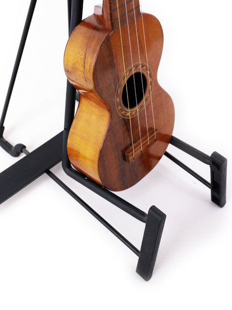 A Kumalae Style 2 ukulele from Hawaii, circa 1913, sits gracefully on a stand, emphasizing its vintage charm and craftsmanship.