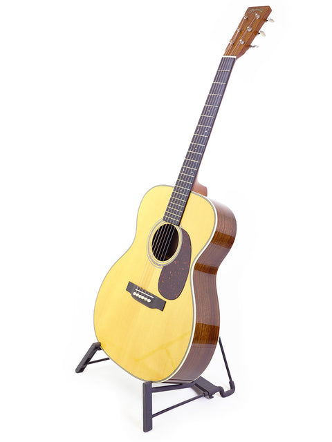 A Martin Custom Shop 000-28 guitar showcased on a stand, featuring a pristine white background for emphasis.