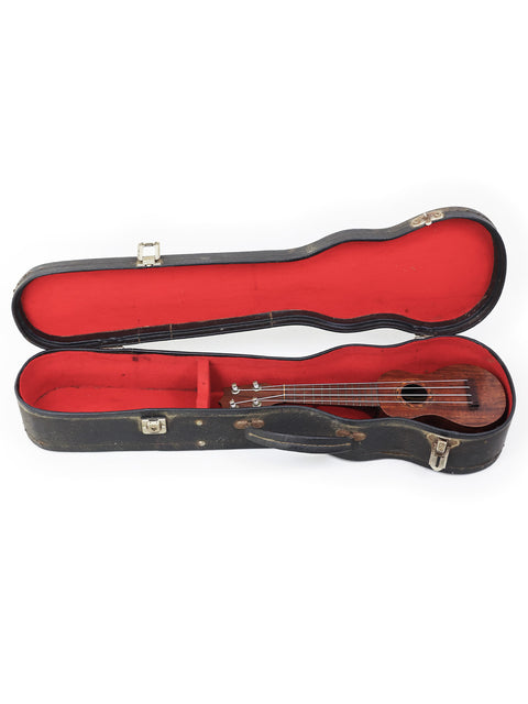 A TABU Style 2 "Midget" Koa Ukulele from 1917, resting in a stylish black case with bold red interior lining.