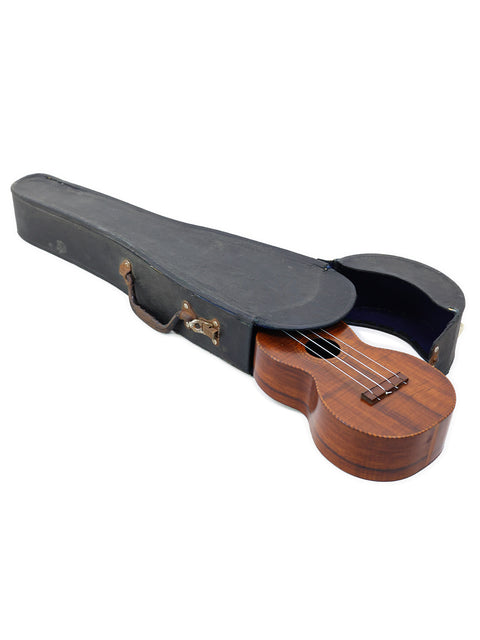 A classic 1927 Paul F. Summers 'Moana' Style 5 Koa Ukulele resting in its case on a white backdrop.
