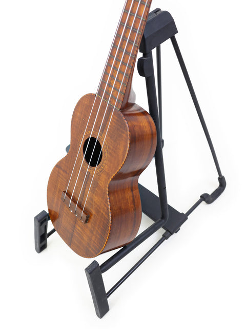 A classic 1927 Paul F. Summers 'Moana' Style 5 Koa Ukulele sits on a stand, highlighting its beautiful craftsmanship.