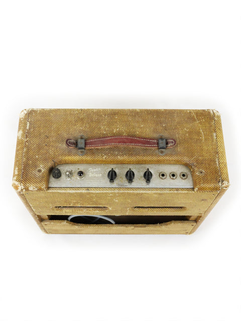A classic 1955 Fender Tweed Deluxe Amp 5D3 displayed on a white surface, highlighting its vintage appeal and craftsmanship.