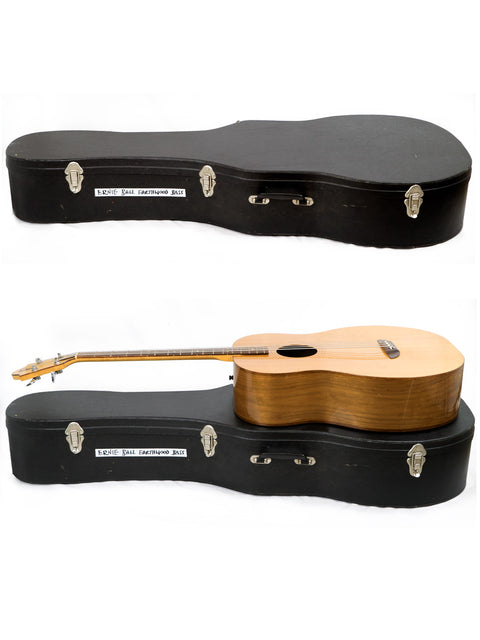 A classic 1980s Ernie Ball Earthwood Bass guitar sits on its case, embodying vintage musical elegance.