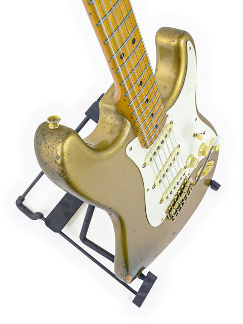 A gold '57 Fender Custom Shop Stratocaster guitar from 1988 resting elegantly on a stand, emphasizing its limited edition status.