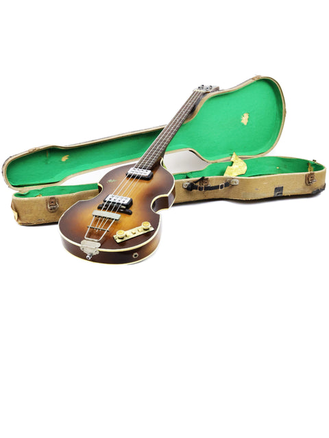 A green-covered case holds a Hofner 500/1 'Beatle Bass' guitar, reflecting its 1962 German craftsmanship and iconic style.

