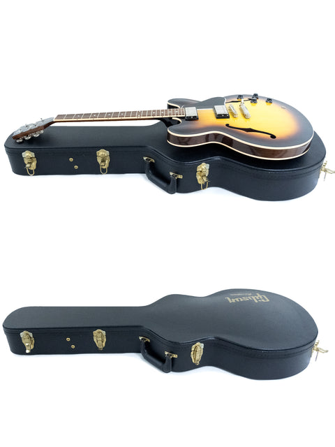 A guitar case holds two guitars, including a 2012 Gibson Custom ES-335 Dot Inlay, highlighting musical artistry.