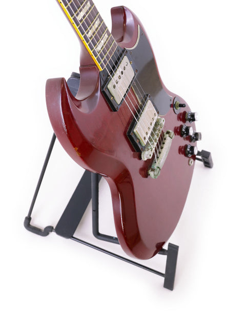 A red Gibson SG '61 Reissue electric guitar from 1988 resting on a stand, highlighting its iconic shape and bold color.