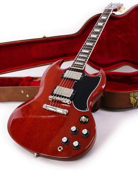 A red Gibson SG Standard ‘61 guitar (2019) with a case and strap, highlighting its iconic shape and color.