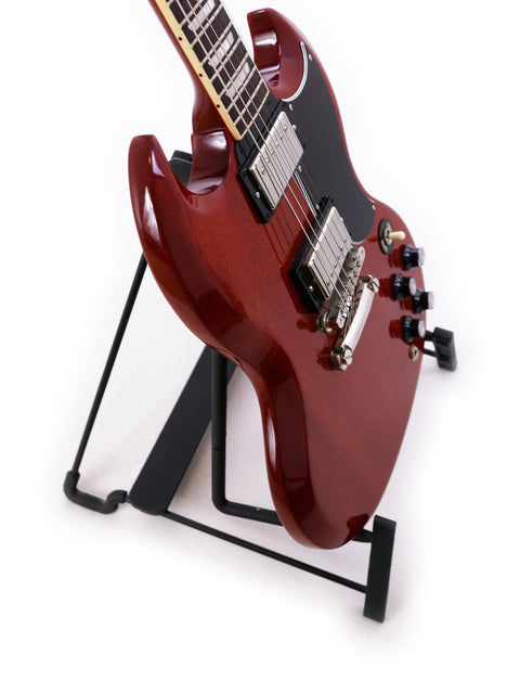 A striking red Gibson SG Standard ‘61 guitar displayed on a sturdy black stand, highlighting its classic appeal.