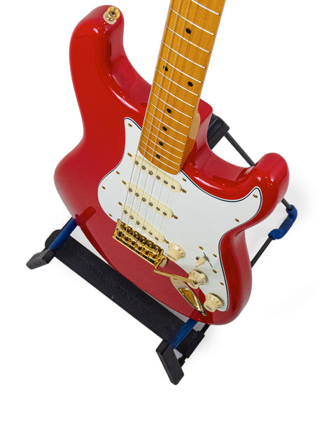 A striking red StrXX Partscaster guitar from 2012 perched on a stand, highlighting its bold color.
