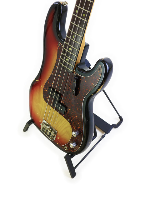 A sunburst-finished vintage Fender Precision Bass guitar from 1972, elegantly positioned on a stand, highlighting its unique features.