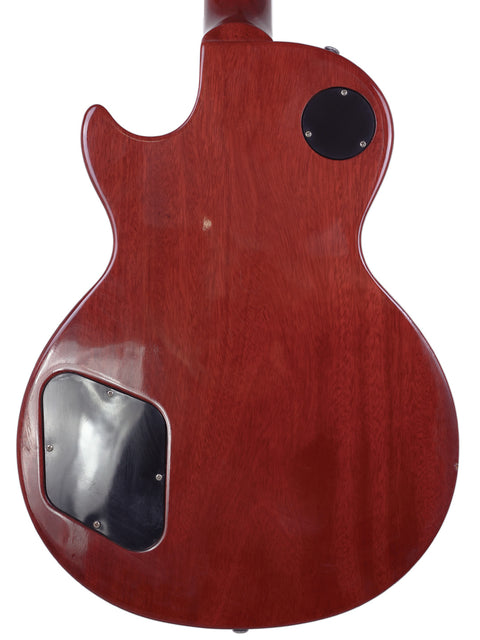 A vibrant red Gibson Les Paul Traditional guitar (2009) with a stylish black pickguard, showcasing its classic design.
