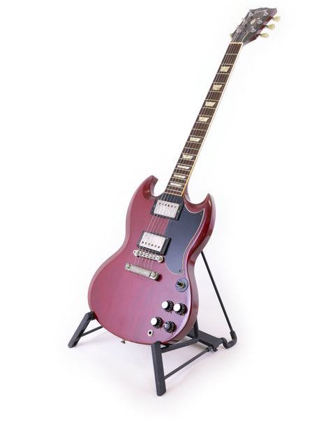 A vibrant red Gibson SG '61 Reissue electric guitar from 1988 rests on a stand, highlighting its classic rock aesthetic.
