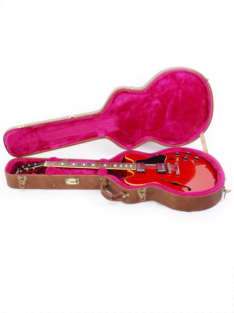 A vibrant red guitar case featuring a pink lining, housing a Gibson ES-335 Block 1963 Nashville Custom Shop from 2000.