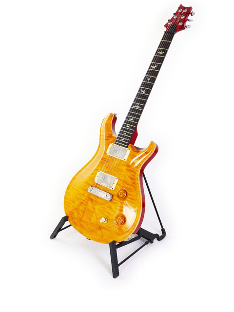  A vibrant yellow PRS Custom 22 guitar from 2005 resting on a stand, emphasizing its striking color and design.