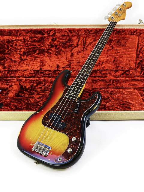 A vintage Fender Precision Bass from 1972, displayed in a case, highlighting its beautiful sunburst finish and '63 neck.