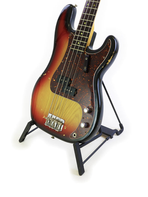 A vintage Fender Precision Bass guitar with a sunburst finish displayed on a stand, showcasing its classic design.