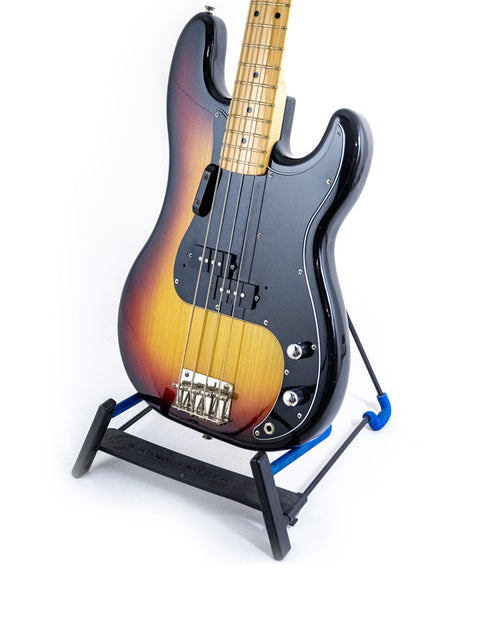A vintage Fernandes P Bass guitar (1978-81) elegantly positioned on a stand with a deep black backdrop.