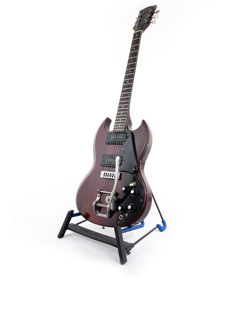 A vintage Gibson SG Pro guitar from 1972 on a stand, featuring a white background.