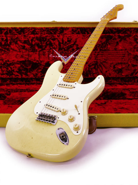 A white guitar, the Fender Ltd Custom 50s Journeyman Stratocaster, rests in a vibrant red case, highlighting its craftsmanship.