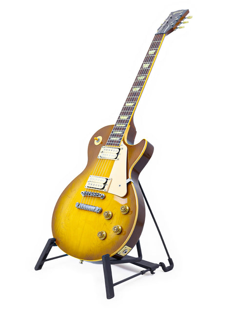 A yellow Gibson Les Paul Classic 1960 Reissue guitar on a stand against a clean white background.
