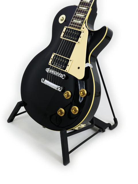 Black electric guitar, Tokai Les Paul Reborn LS50, Japan 1979, elegantly positioned on a stand.