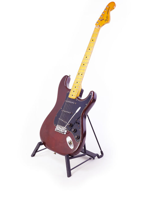 Brown vintage Fender Stratocaster guitar from 1979 on a stand, set against a bright white background.