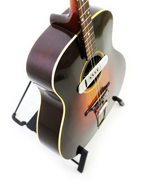 Classic 1934 Gibson TG50 Tenor Guitar displayed on a stand, perfect for collectors and music enthusiasts, set on a white backdrop.
