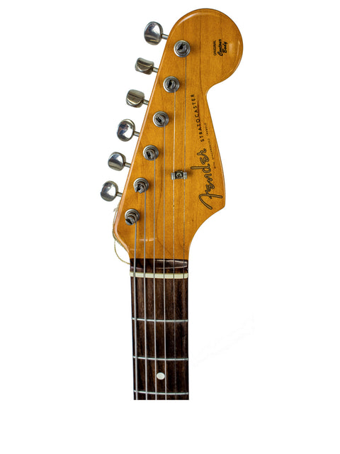 Close-up of a Fender American Vintage 62 Strat guitar headstock in Fiesta Red, showcasing its wooden texture and craftsmanship.
