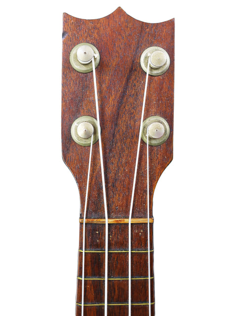 Close-up of a TABU Style 2 "Midget" Koa Ukulele, showcasing its wooden neck and strings, crafted in Hawaii around 1917.