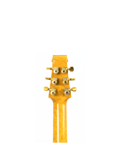 Close-up of a golden guitar headstock with tuning pegs on a white background.