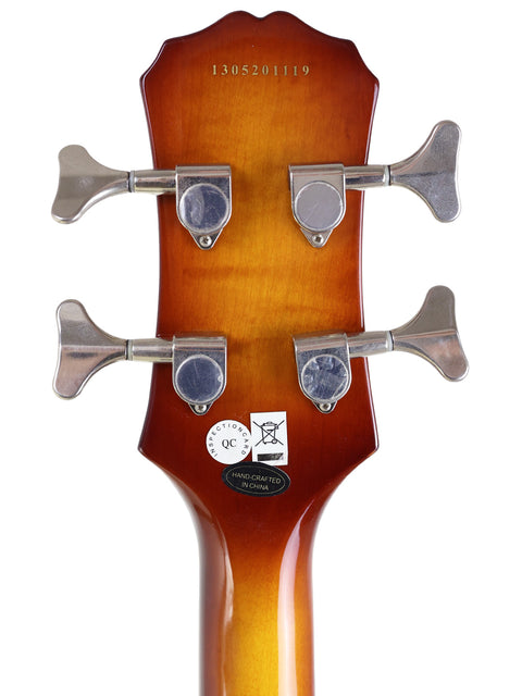 Close-up of a guitar headstock with tuning pegs and a quality control sticker.