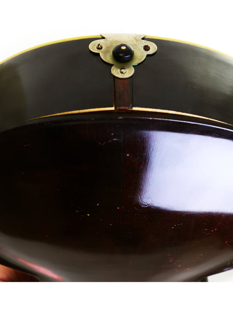 Close-up of a vintage black and gold bowl, reflecting the artistry of the 1920 Gibson L-1 guitar.