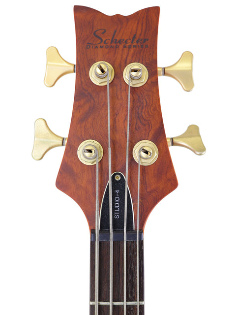 Close-up of the gold headstock on a Schecter Stiletto Studio 4 Bass guitar, highlighting its elegant craftsmanship.