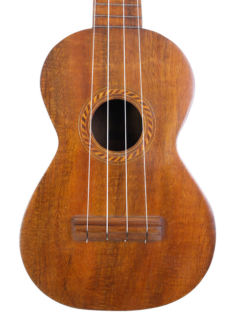 Close-up of the soundhole and strings on the Aloha/Akai Style 2 Concert Ukulele, highlighting the detailed wood grain and decorative rosette pattern.