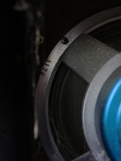  Close-up shot of a vintage VOX AC50 MKII speaker from 1968, featuring a distinctive blue button for a retro touch.