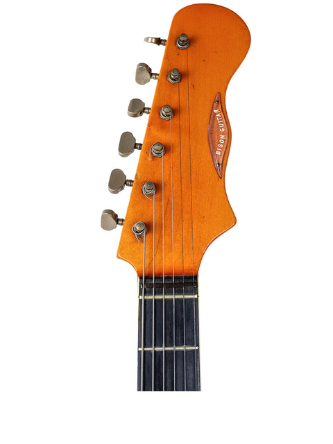 Detailed view of an orange headstock from a 1964 Burns Black Bison guitar, featuring a striking transparent red finish.
