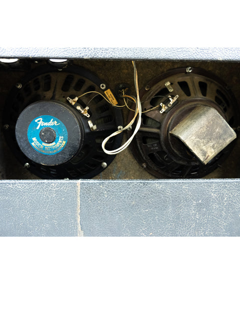 Detailed view of two speakers nestled in a 1977 Fender Vibrolux Reverb Amp, featuring a classic Silverface metal box.