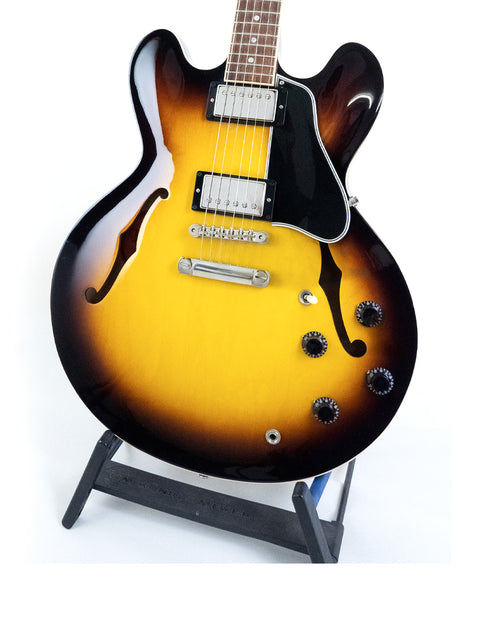 Gibson Custom ES-335 guitar with a striking sunburst finish, resting on a stand, showcasing dot inlays from 2012.