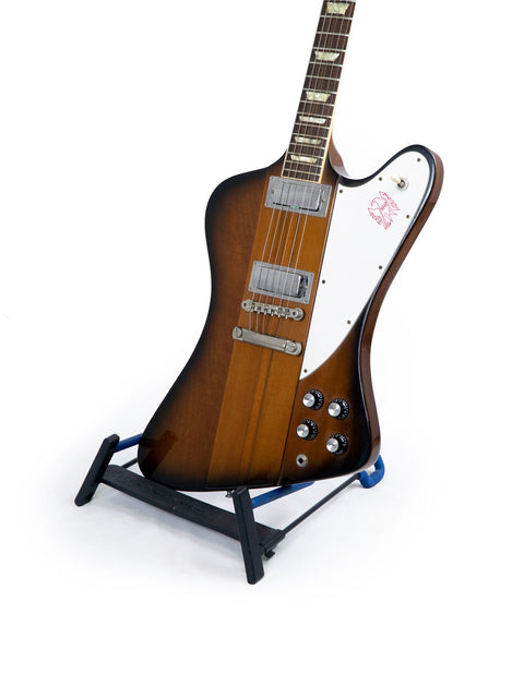 Gibson Firebird V Reissue guitar on a stand, set against a clean white background, showcasing its sleek design.