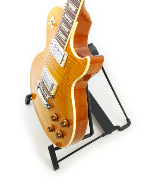 Gibson Les Paul Standard guitar on a stand, set against a clean white background, showcasing its elegant design.