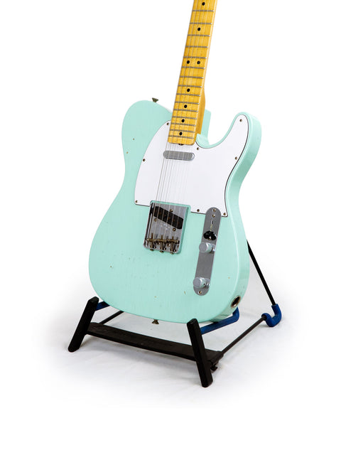 Green Fender Custom Shop 60s Journeyman Telecaster guitar displayed on a black base stand, highlighting its craftsmanship.
